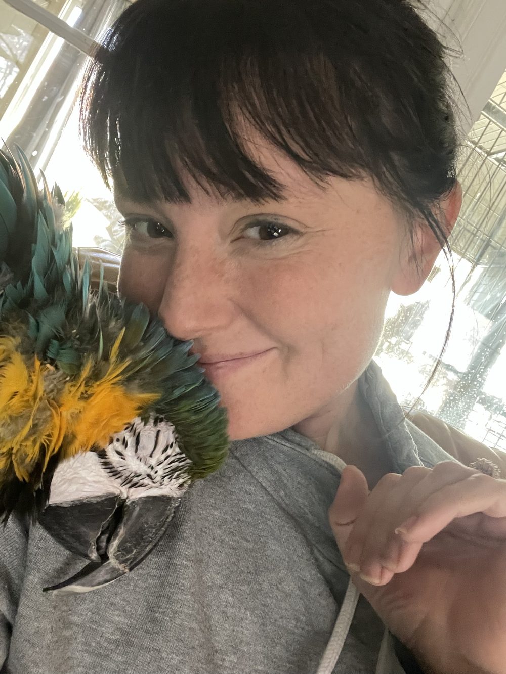 Brittany cheek to cheek with Kya, a blue-and-gold macaw, resting on her shoulder